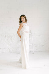 Modelo de pie y de perfil luciendo una combinación perfecta para una boda minimalista: un vestido dos piezas novia con pantalón