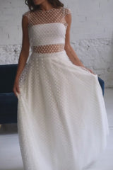 Video de modelo con un vestido de novia dos piezas con crop top de manga corta en tela de tul de florecitas blancas.