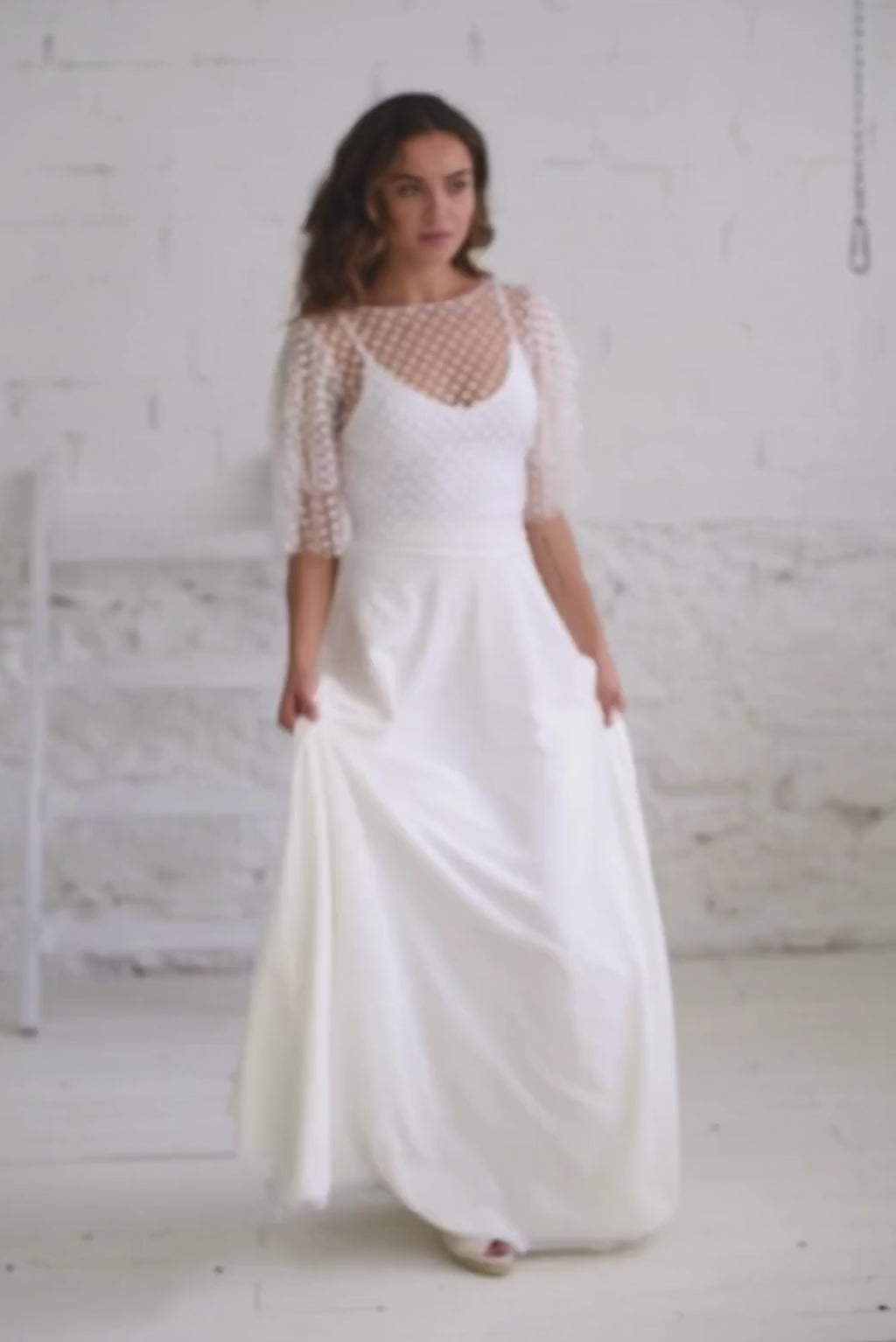 Video de modelo andando y moviendose la falda de su vestido de novia con crop top de mangas tres cuartos de florecitas blancas.