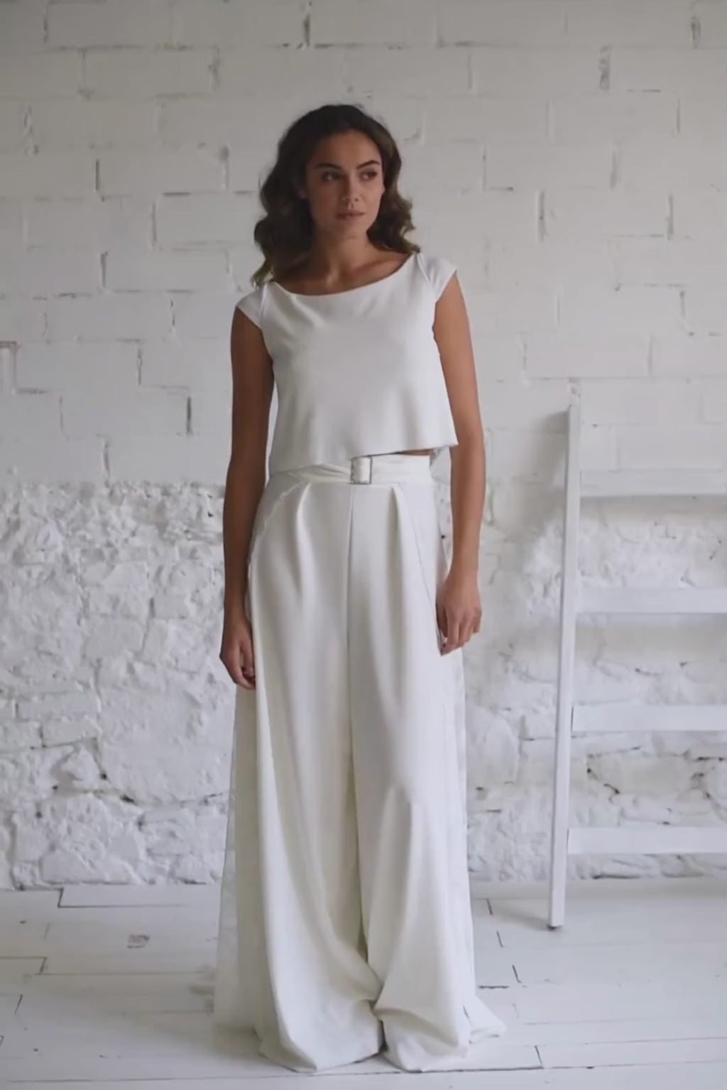 video de modelo andando a camara con crop top blanco de novia con espalda abierta y mangas cortas.