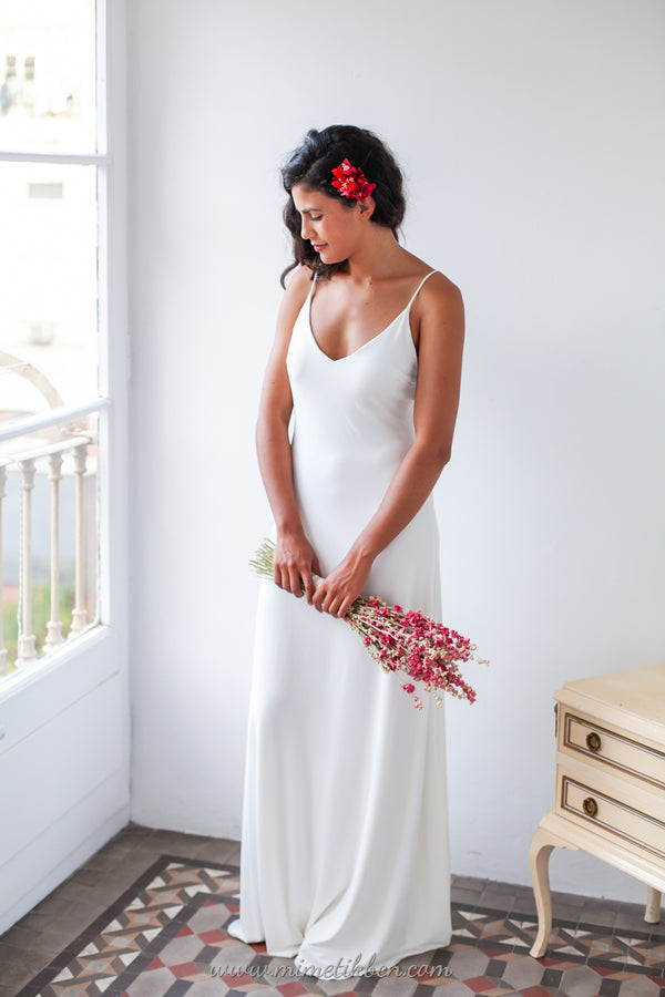 Vista frontal de una hermosa novia luciendo el elegante vestido de novia Marie en blanco, con detalles de encaje y un ramo de flores