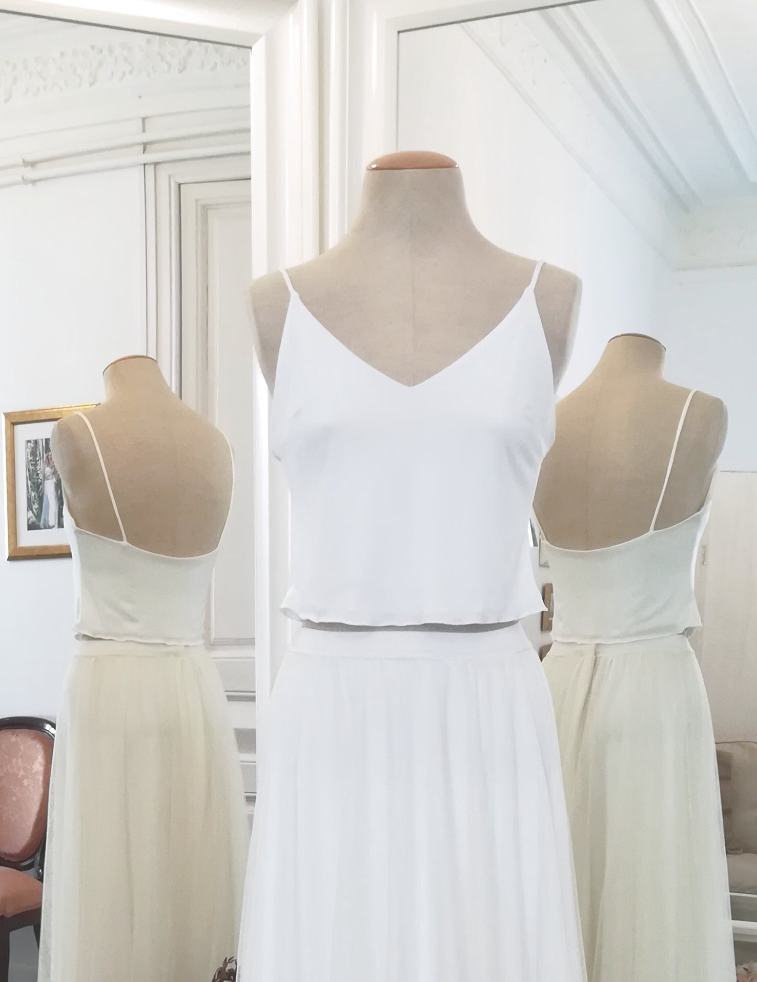 Un top de novia sencillo con tirantes descansa en un busto en el atelier.