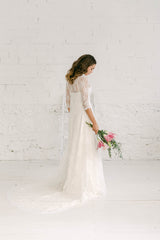 Modelo de espaldas a cámara con impresionante vestido de novia con cola larga de encaje.