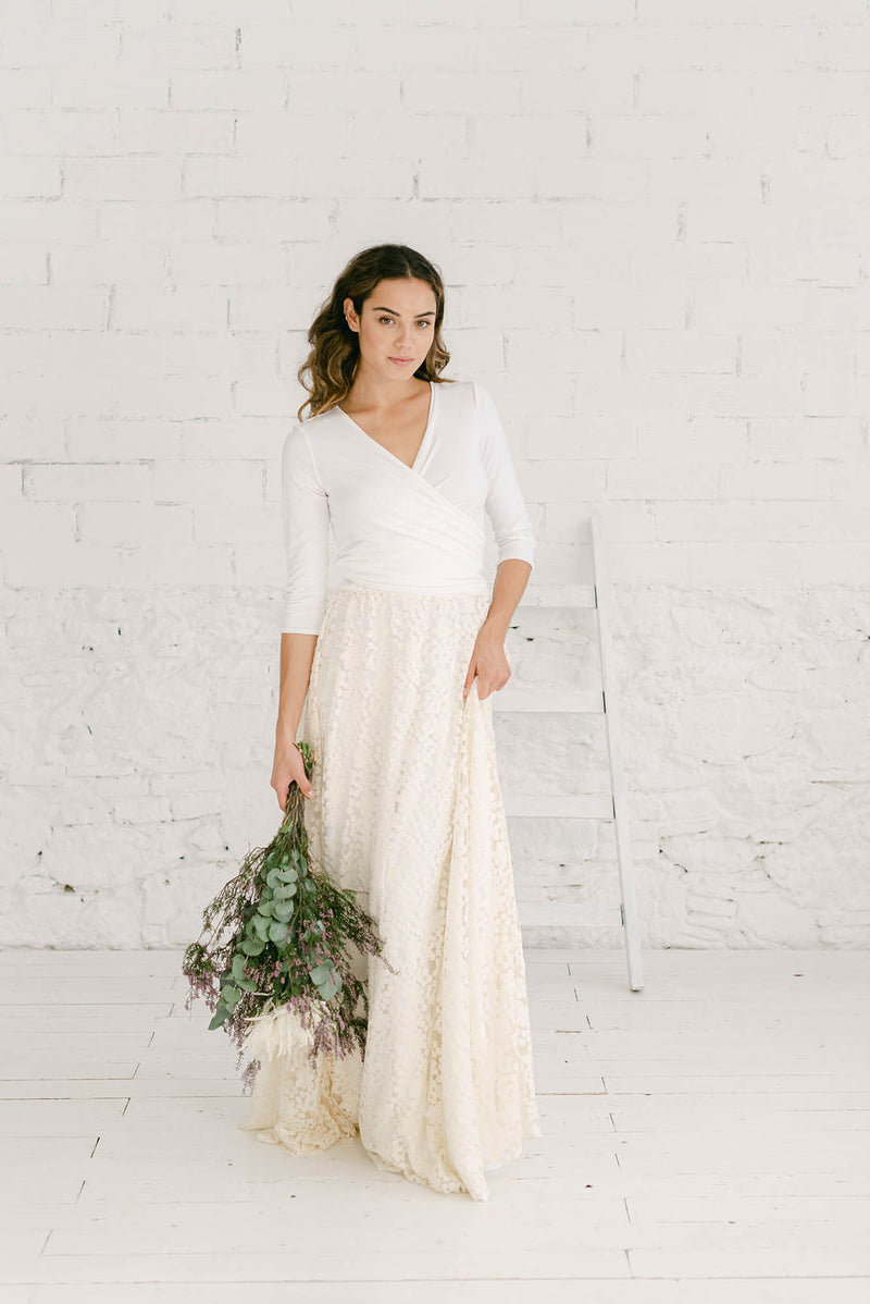 Chica con vestido de novia dos piezas con sobrefalda de encaje de flores bordadas en color crema.