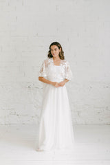 Modelo cchica con vestido de novia dos piezas blanco con top de capa corta en tela de encaje blanco.